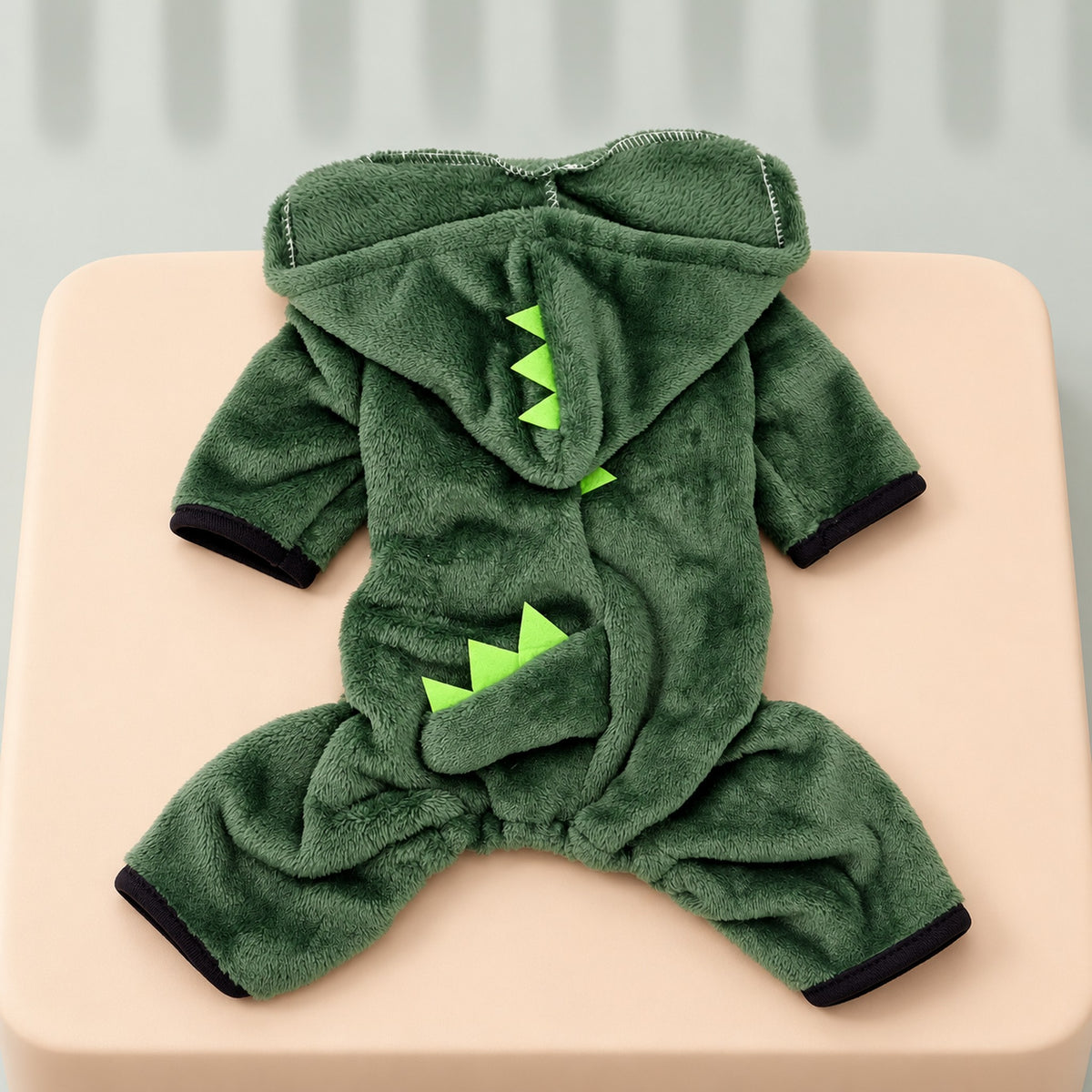 Green dinosaur jumpsuit laid flat from the back: spiked hood, short spiked tail flap and four legs with black cuffs