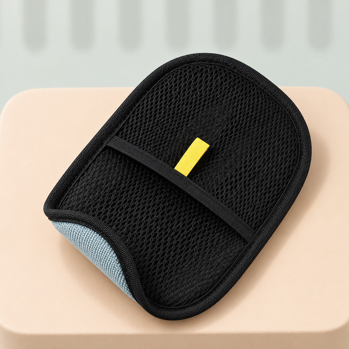 One hair remover glove, black mesh side up, with the yellow tab above the elastic band and a corner turned back to show the gray pad