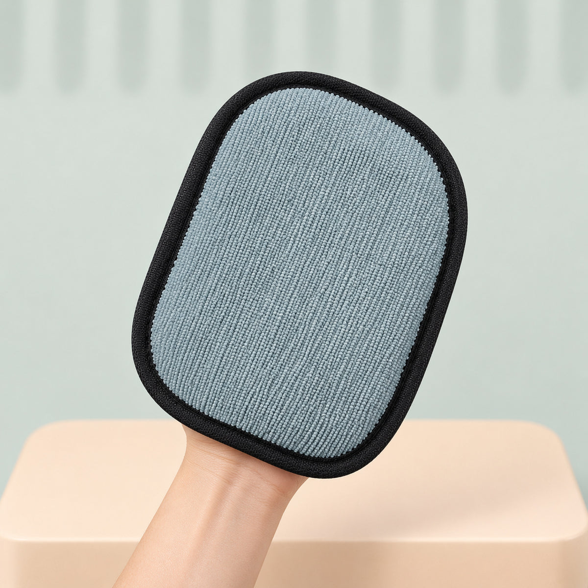Glove held up to show its gray-blue wiping pad