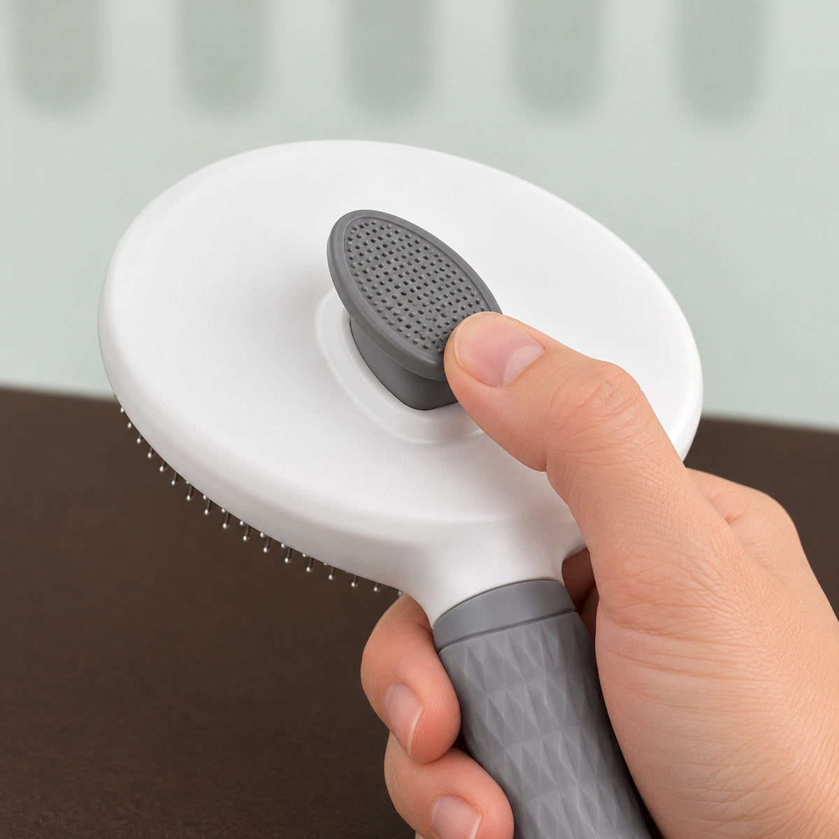 Thumb pressing the push button on the back of the slicker brush head